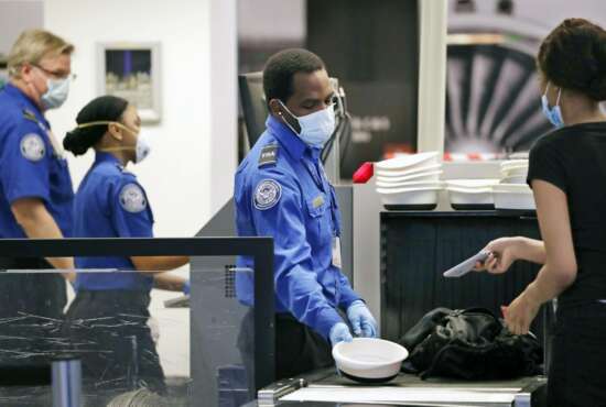 FILE - In this May 18, 2020, file photo, Transportation Security Administration officers wear protective masks at a security screening area at Seattle-Tacoma International Airport in SeaTac, Wash. The Biden administration says it is moving to increase the pay and union rights for security screeners at the nation’s airports. The Department of Homeland Security directed the acting head of the TSA to come up with a plan within 90 days to raise the pay of the screeners and expand their rights to collective bargaining.  (AP Photo/Elaine Thompson, File)