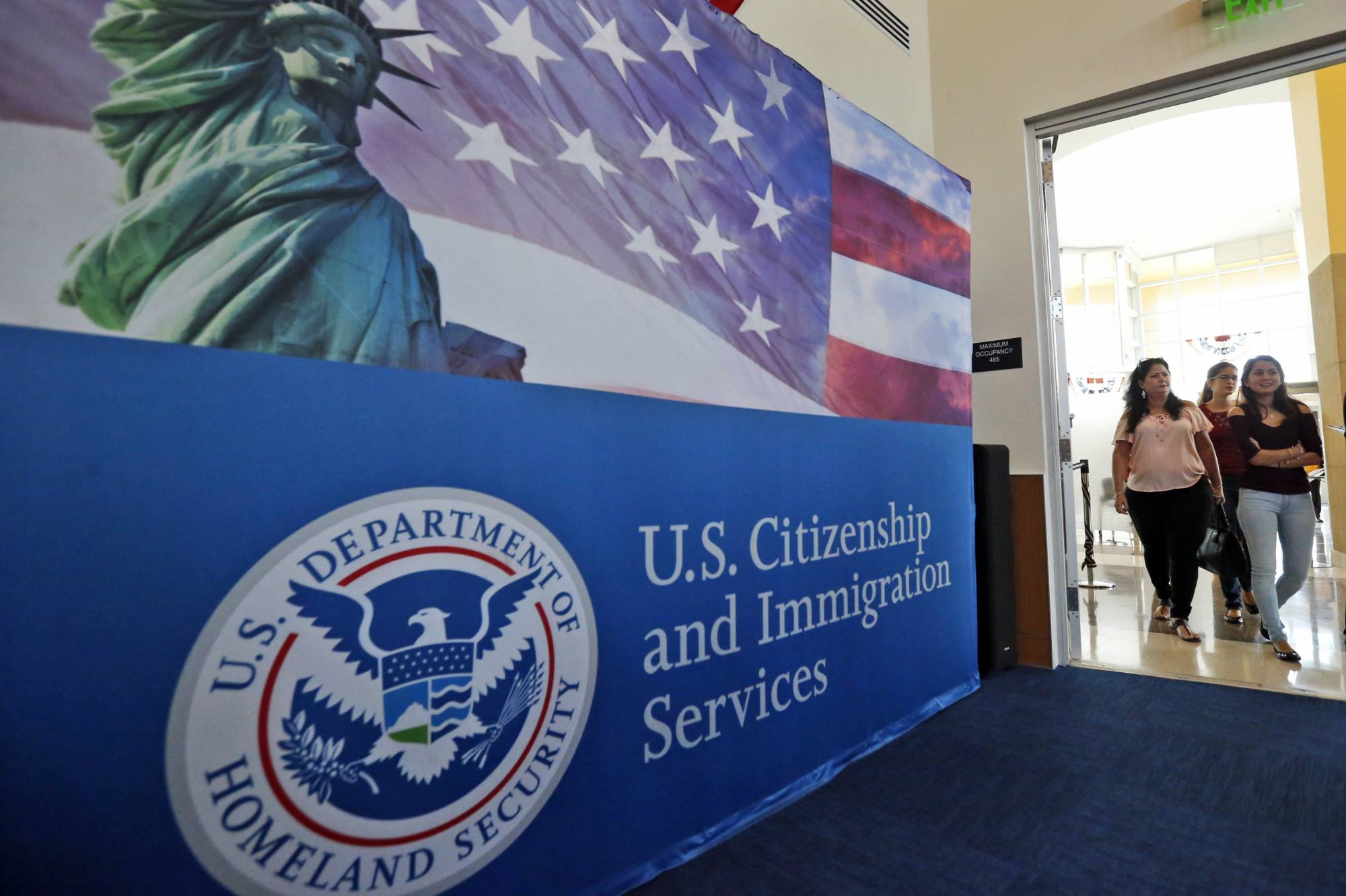 FILE - In this Aug. 17, 2018, file photo, people arrive before the start of a naturalization ceremony at the U.S. Citizenship and Immigration Services Miami Field Office in Miami. USCIS, The cash-strapped federal agency that oversees that nation's legal immigration system, scrapped plans Tuesday, Aug. 25, 2020, to furlough 13,000 employees, or nearly 70% of its workforce. The agency said it would maintain operations through September when the the fiscal year ends.  (AP Photo/Wilfredo Lee, File)