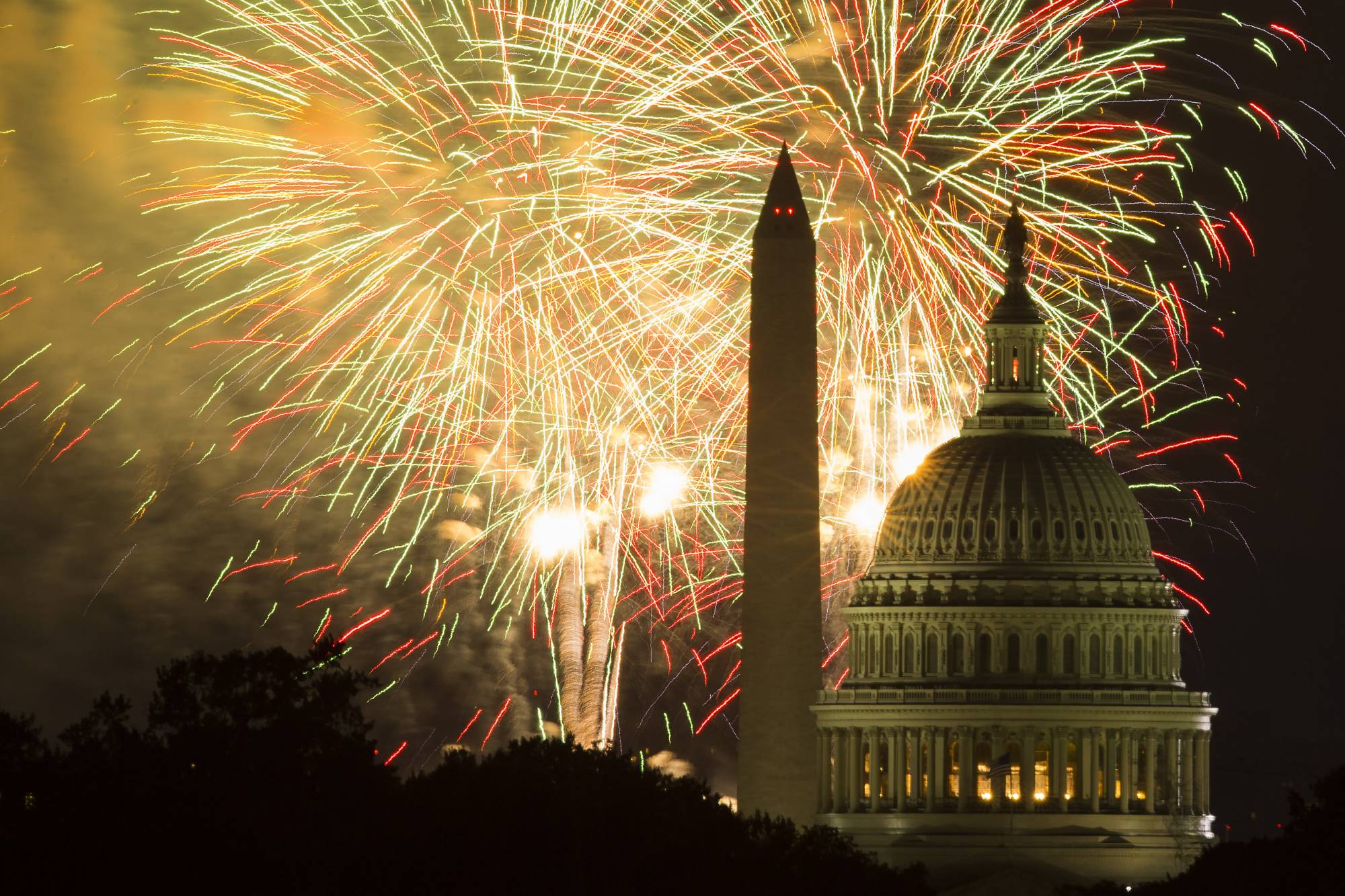 FILE - In this July 4, 2014 file photo, fireworks illuminate the sky over the U.S. Capitol building and the Washington Monument during Fourth of July celebrations in Washington.    PBS’ tradition of broadcasting music and fireworks from the West Lawn of the U.S. Capitol is facing competition from a different live concert in the same city at the same time hosted on the White House’s South Lawn. Though each event will feature competing “American Idol” alums, the PBS’ “A Capitol Fourth” has the bigger stars: The Beach Boys, Jimmy Buffett, Pentatonix, Chita Rivera, Luke Combs, The Temptations, Renee Fleming, CeCe Winans, Joshua Bell and “American Idol” singer Lauren Alaina. It will be hosted by John Stamos.(AP Photo/Evan Vucci, File)